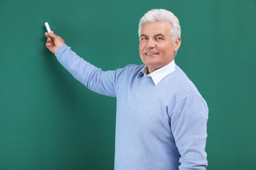 Portrait of senior teacher with chalk at green board