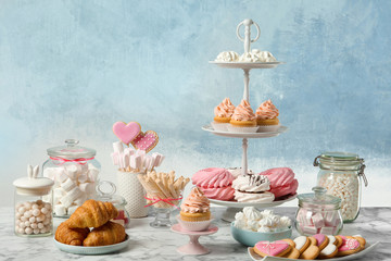 Candy bar with different sweets on white marble table against color background