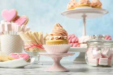 Stand with cupcake and other sweets on white marble table. Candy bar