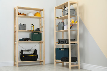 Wooden shelving units with different instruments near color wall. Stylish room interior