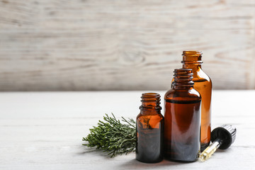 Composition with bottles of conifer essential oil on white wooden table. Space for text