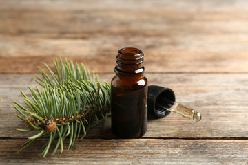 Composition with bottle of conifer essential oil on wooden table