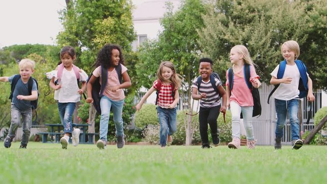 Excited Elementary School Pupils Running Across Field At Break Time