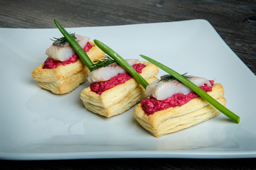 closeup snacks with red sauce, herring pieces, green onion