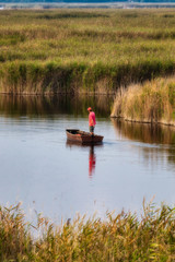 Fototapeta na wymiar Fisherman paddling a boat on the lake in Hungary