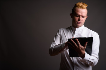 Businessman with Mohawk hairstyle and blond hair against gray ba