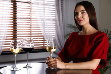 Beautiful young woman tasting luxury wine at table. Space for text