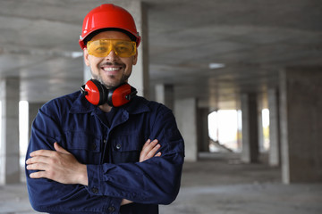 Professional engineer in safety equipment at construction site, space for text