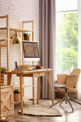 Stylish room interior with modern workplace at brick wall