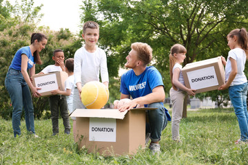 Volunteers and kids with donation boxes in park