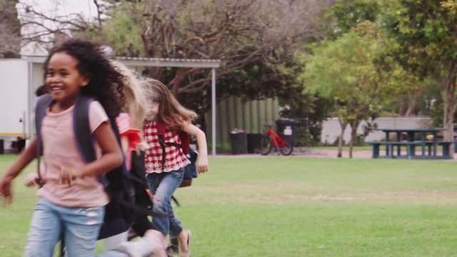Excited Elementary School Pupils Wearing Uniform Running Across Field At Break Time