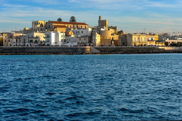 Fototapeta premium Modern residential buildings do not hide the medieval buildings - the cathedral, bell tower and fortress walls.В этот воскресный вечер набережная была полна отдыхающими.