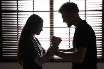 Man abusing woman near window. Stop sexual assault
