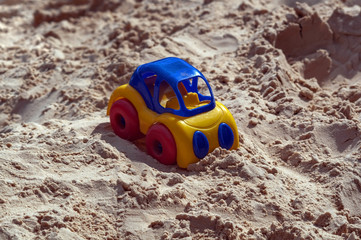 Children's multi-colored plastic machine on the background of sand