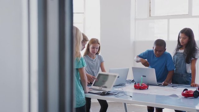 Students With Female Teacher In After School Computer Coding Class Learning To Program Robot Vehicle
