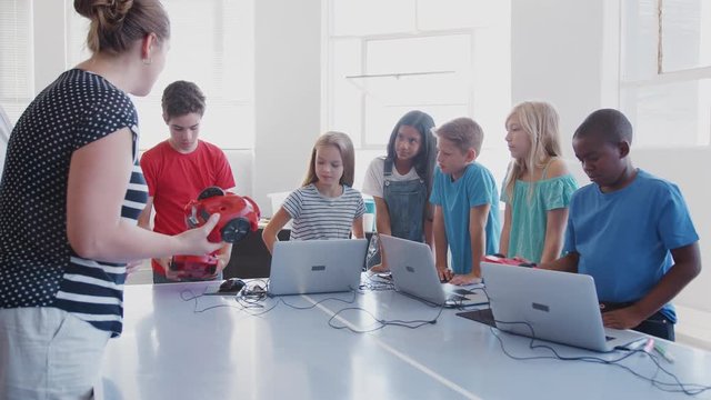 Students With Teacher In After School Computer Coding Class Learning To Program Robot Vehicle