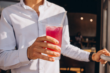 photo of a man's hand holding a glass of cool summer cocktail. A man moves with a lemonade to the summer terrace