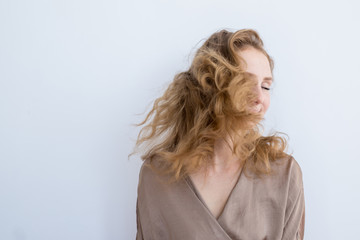 Portrait of a young beautiful girl who waves hair on a white background.