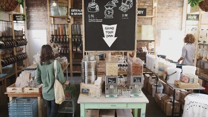 Shoppers Looking At Products In Sustainable Plastic Free Grocery Store