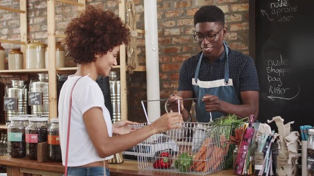 Customer Paying For Shopping At Checkout Of Sustainable Plastic Free Grocery Store