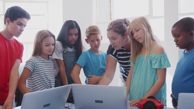 Students With Female Teacher In After School Computer Coding Class Learning To Program Robot Vehicle