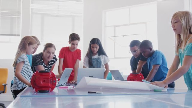 Students With Teachers In After School Computer Coding Class Learning To Program Robot Vehicle