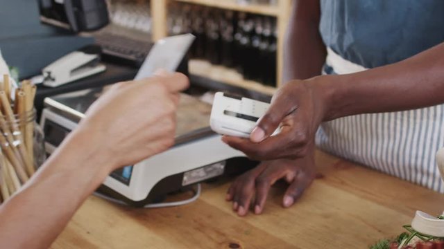 Close Up Of Customer Making Contactless Payment For Shopping At Checkout Of Grocery Store