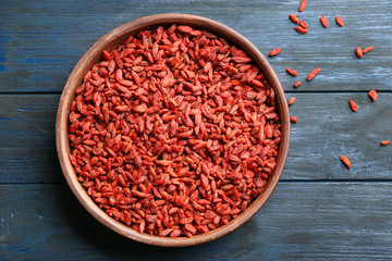 Bowl of dried goji berries on wooden table, top view. Healthy superfood