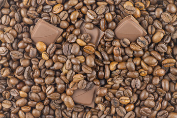 Pieces of milk chocolate lie among coffee beans.