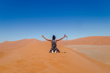 Homme à genoux dans le sable dans le désert en Namibie en Afrique