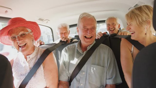 Group Of Senior Friends Sitting In Back Of People Carrier Being Driven To Vacation