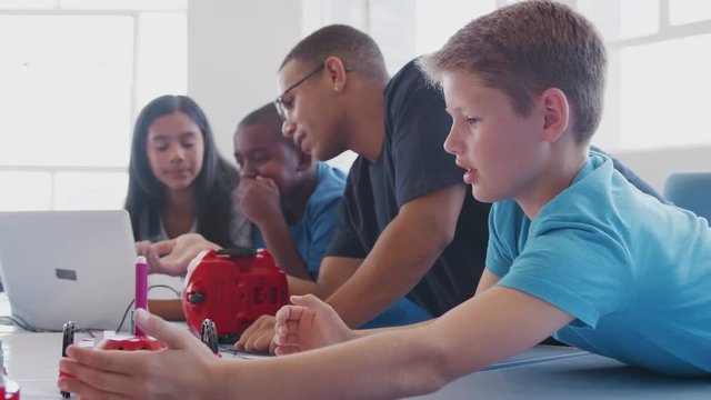 Students With Male Teacher In After School Computer Coding Class Learning To Program Robot Vehicle