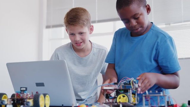 Two Male Students Building And Programing Robot Vehicle In After School Computer Coding Class 