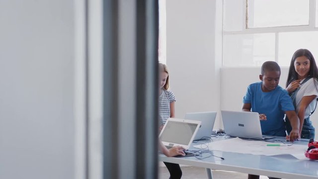Students With Female Teacher In After School Computer Coding Class Learning To Program Robot Vehicle