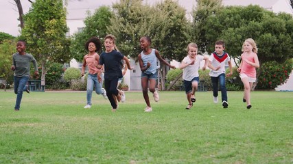 Group Of Excited Children Playing With Friends And Running Across Grass Playing Field - Powered by Adobe