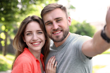 Obraz premium Happy young couple taking selfie in park
