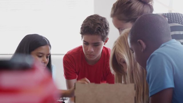 Students With Female Teacher In After School Computer Coding Class Learning To Program Robot Vehicle