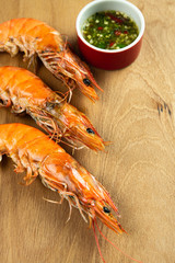 Closeup mouth-watering grilled shrimps with spicy sauce delicious Thai seafood on wooden table background.