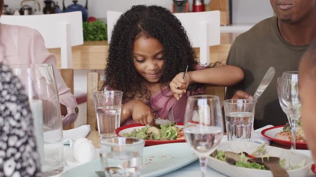 Multi-Generation Family Sitting Around Table At Home Enjoying Meal Together