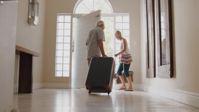 Senior Couple With Suitcase Opening Front Door And Leaving For Vacation