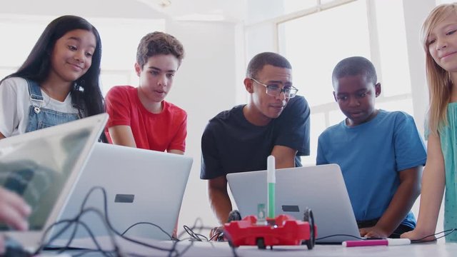 Students With Male Teacher In After School Computer Coding Class Learning To Program Robot Vehicle