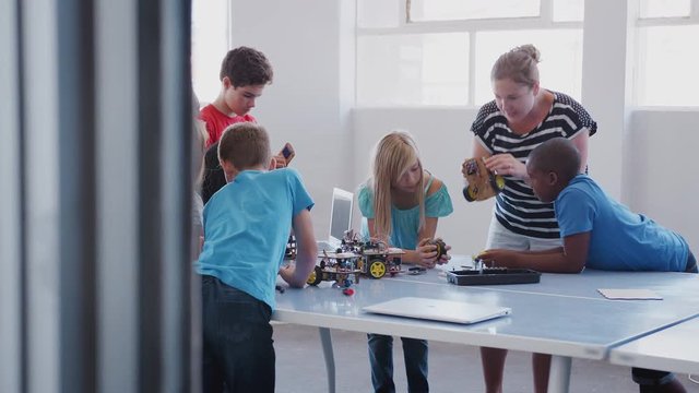 Students With Teachers In After School Computer Coding Class Learning To Program Robot Vehicle