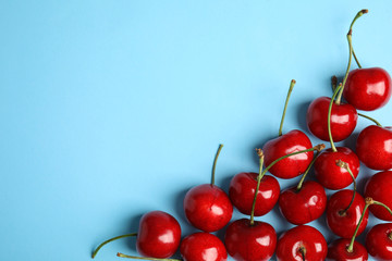 Obraz na płótnie Canvas Composition with sweet cherries on light blue background, top view. Space for text