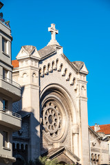 Part of the facade of a historic church between modern houses in Nice, France.