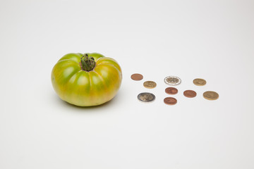 Tomate verde y monedas a su lado. El precio de los productos. Lo que cobra el agricultor por sus cosechas.
