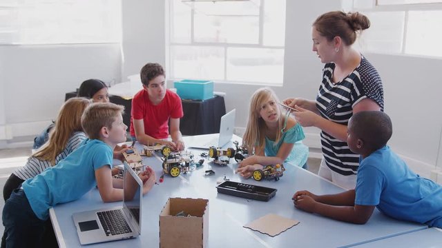 Students With Female Teacher In After School Computer Coding Class Learning To Program Robot Vehicle
