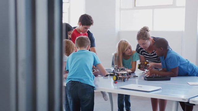 Students With Teachers In After School Computer Coding Class Learning To Program Robot Vehicle