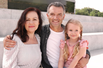 Fototapeta premium Couple of pensioners with granddaughter sitting outdoors