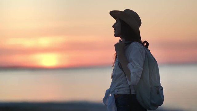 Tired travel backpacker female relaxing at sunset enjoying evening beautiful seascape medium shot