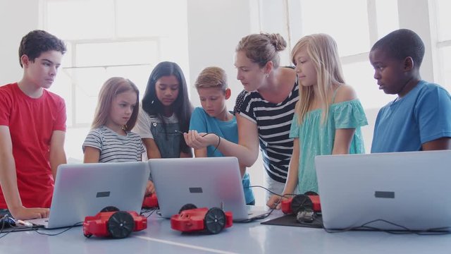 Students With Female Teacher In After School Computer Coding Class Learning To Program Robot Vehicle